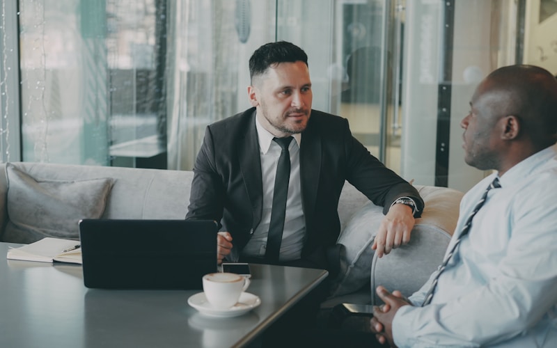 Two business owners discussing their startup over coffee at a café table with a laptop